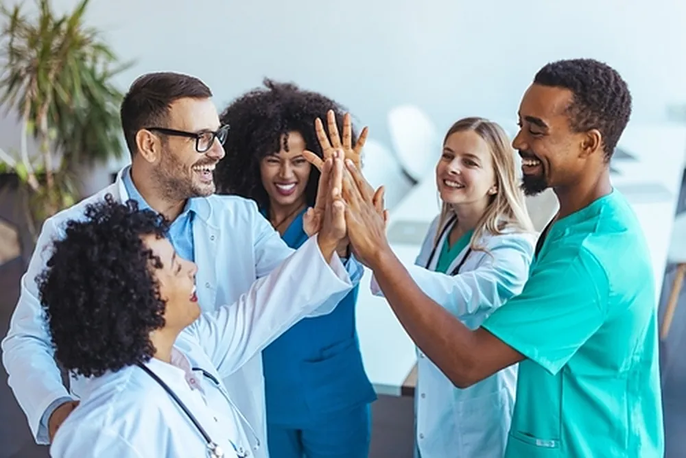 A care team of therapists and clinicians celebrating together with a high five